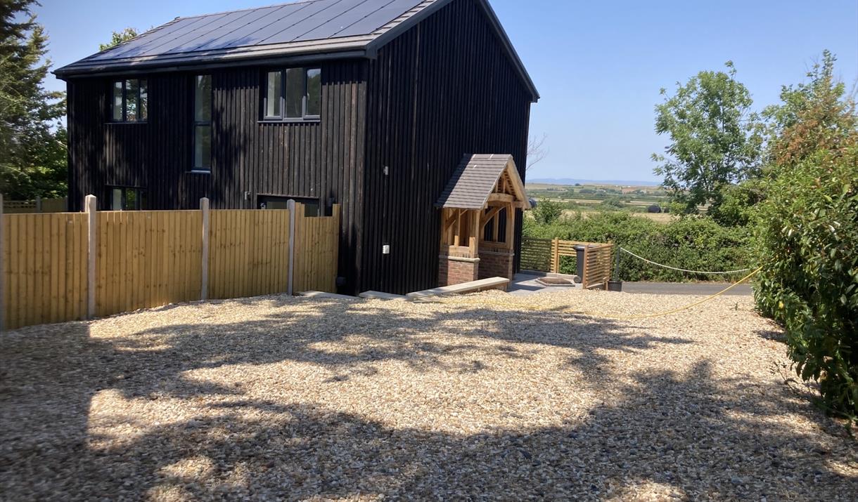 Outside view of a black wooden house and a shingle drive