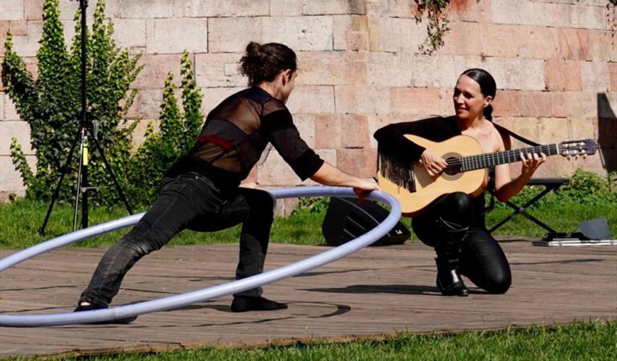 Lady playing guitar, man inside large hoop