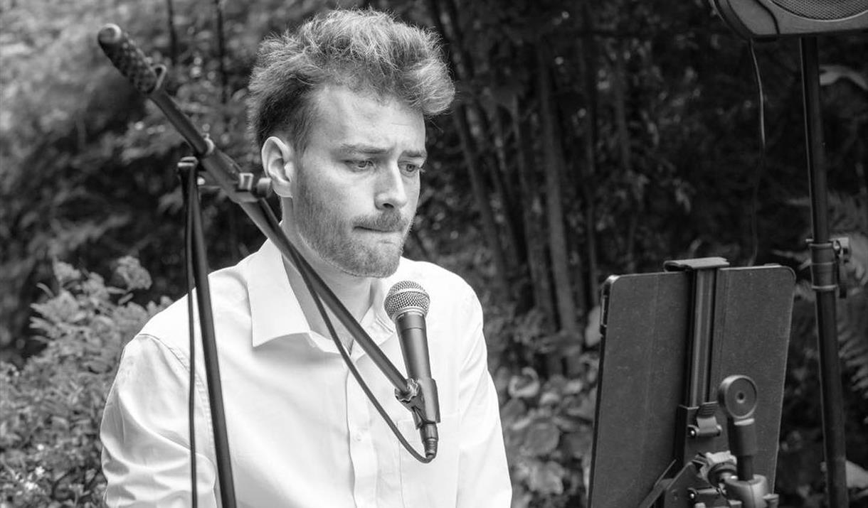 black and white picture of the artist at a keyboard in woodlands