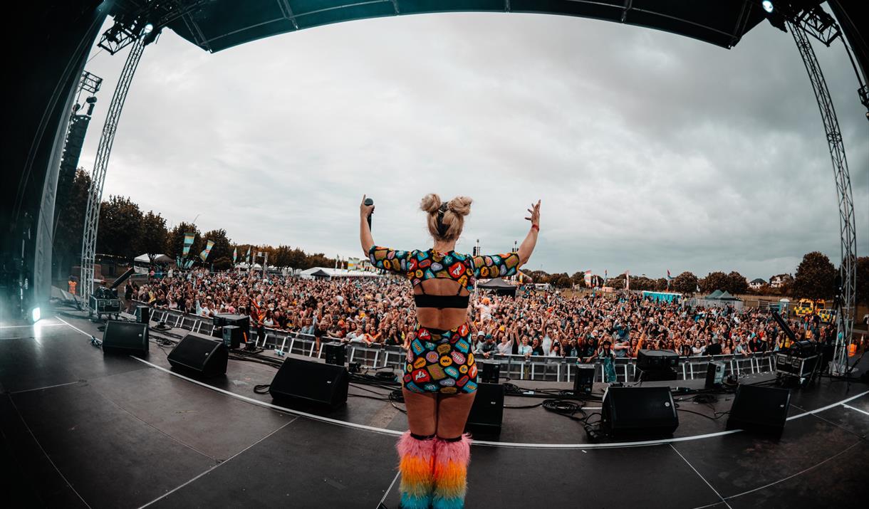 A brightly dressed performer on stage in front of a huge crowd