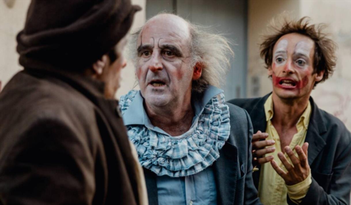 2 clowns looking at another, one is pleading