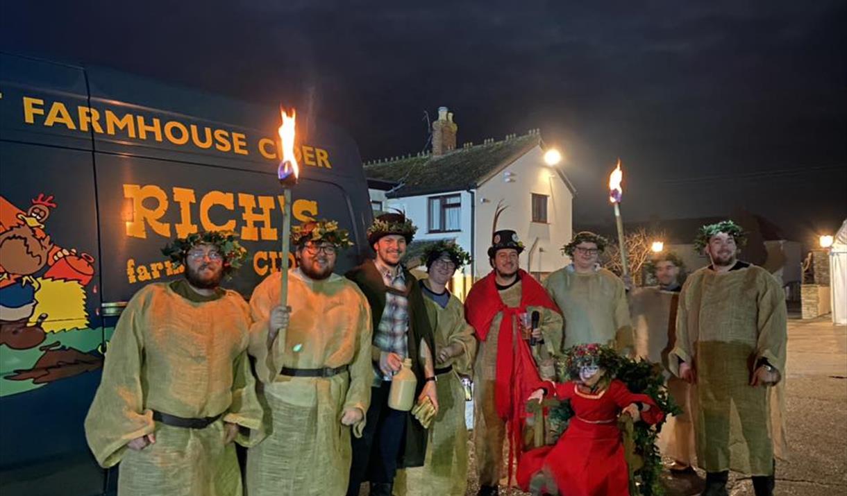 People in wassail costume in front of a van