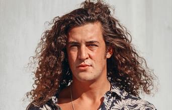 Portrait of singer songwriter Harrisen Larner-Main with his long curly hair and open necked shirt