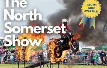 A motorbike stunt rider riding through a flaming arch on a poster advertising the North Somerset Show