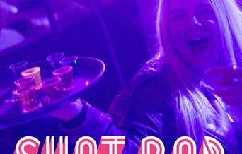 A lady in a nightclub holding a tray of shots