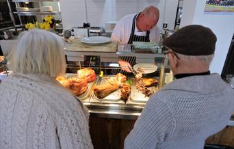 A chef serving two people a carvery