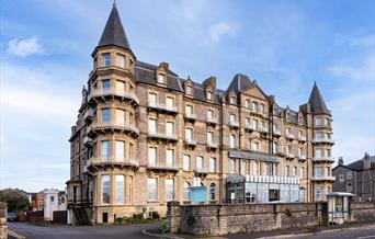 Exterior of a big four-storey hotel with turrets on the corners