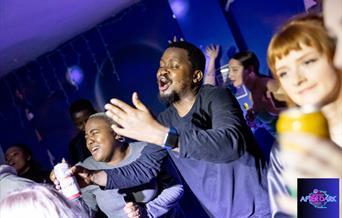 A group of adults singing karaoke in an adults soft play party night