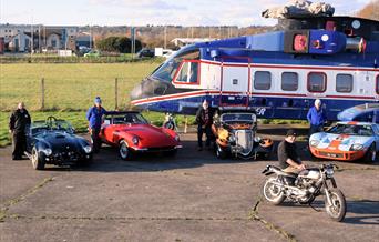 Vintage cars and an old helicopter on display at the Weston-super-Mare Helicopter Museum