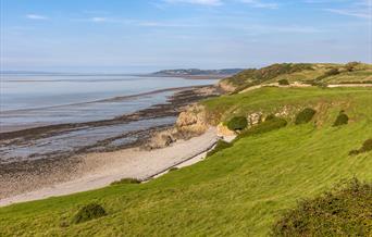 A green field looking down onto a shingle beach