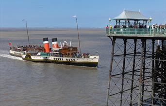 A full paddle steaming coming in to dock by a pier