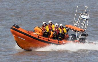 Four members of the RNLI on board an inflatable lifeboat
