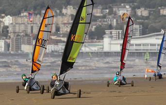 Four land yachts racing across a beach