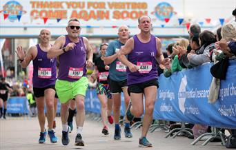 A group of runners being cheered by the crowd