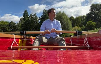 A man rowing a red rowing boat