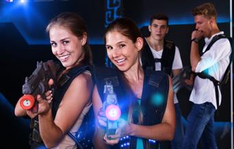 Two girls firing laser guns with two males in the background