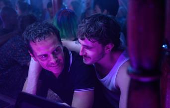 A still from the film. Paul Mescal has their arm around Andrew Scott who is looking out of shot