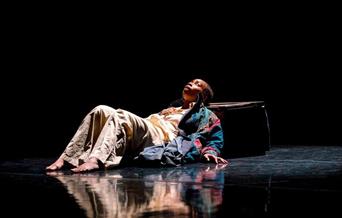 A dance performer lying on the floor looking upwards