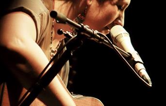 Woman looking at guitar, playing