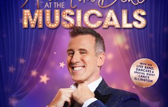 Strictly Come Dancing Star Anton Du Beke tightening the top button of his shirt and looking at the camera