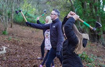 A family of four participating in axe throwing