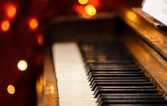 A piano keyboard with a bokeh of Christmas lights in the background