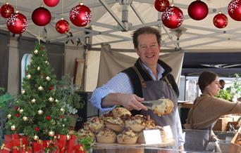 A stallholder serving up a savoury delight at the Eat:Weston food festival on his stall which is decorated with Christmas baubles and a Christmas tree