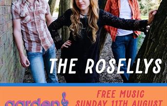 Four members of a band leaning against a wall and trees