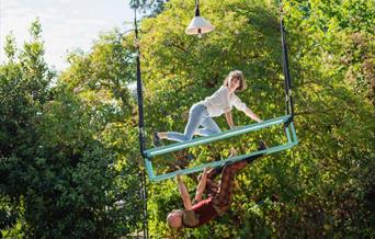 A photo of two people suspended in mid-air from a luggage rack