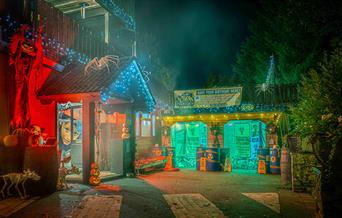 Mendip Activity Centre's outdoor reception area at night - decorated with Halloween decor, pumpkins, giant spiders, zombie apocalyptic banners and red