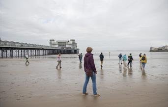 Photograph of people walking on the beach near The Grand Pier