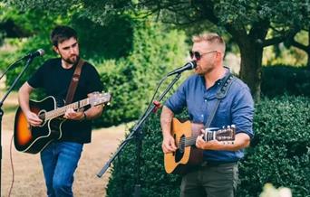 Photograph of the Chicken Teddys playing guitars and singing into microphones.