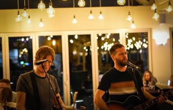 Photograph of Alex and Adam Lipinski singing into microphones at Revo Kitchen