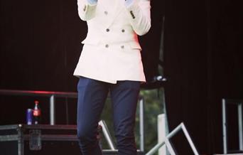 Photograph of Russell Jones Jnr. live on stage, singing into a microphone.