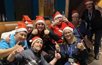 A group of ladies with Learning Disabilities wearing Christmas hats.