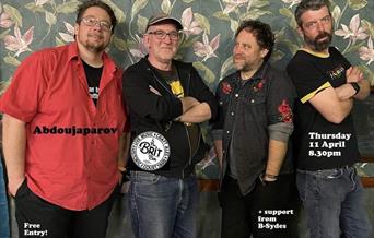 Photograph of the band stood in front of floral wallpaper