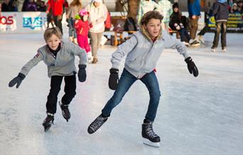 Two boys in grey jackets ice skating