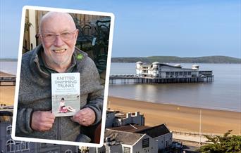 A man holding the book he has written is the inset image, over the main picture of a pier jutting out to sea from a sandy beach