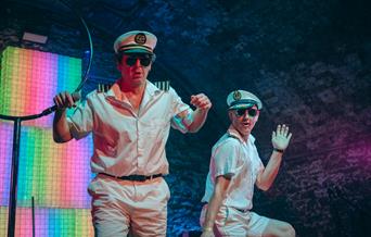 Two men on stage wearing uniforms associated with ship captains