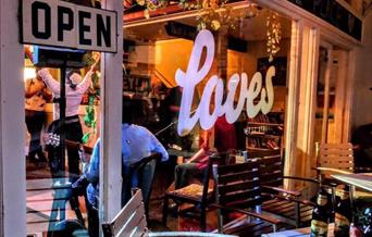 Looking from outside at night through a window into the Weston-super-Mare music and cafe bar Loves