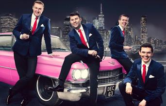 Frankie Valli and band sitting on a pink Cadillac