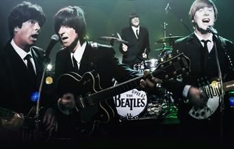 The Upbeat Beatles - photograph of tribute band as the Beatles playing instruments