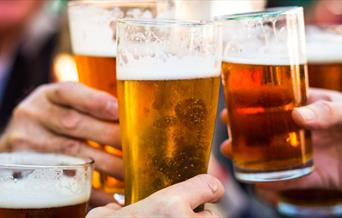 Close up of hands holding three pints of beer