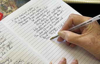 Hand holding pen writing on a notebook