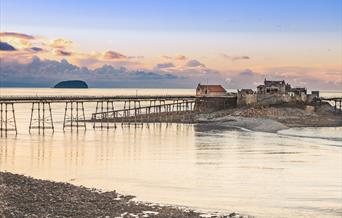 A view of Weston-super-Mare's Birnbeck Pier at sunset with the island of Steep Holm in the background