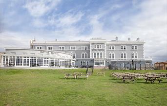 View to a palatial large hotel with a large lawn in the foreground