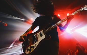 Silhouette of a performer with big hair and a rock guitar