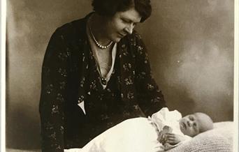 A sepia-toned photograph of a woman looking down at a baby