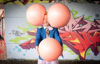 A man juggling 3 large inflatable balls