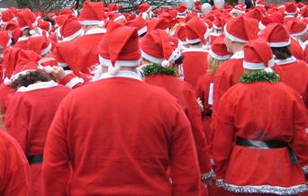 Dozens of people dressed in red Santa suits ready to start a fun run